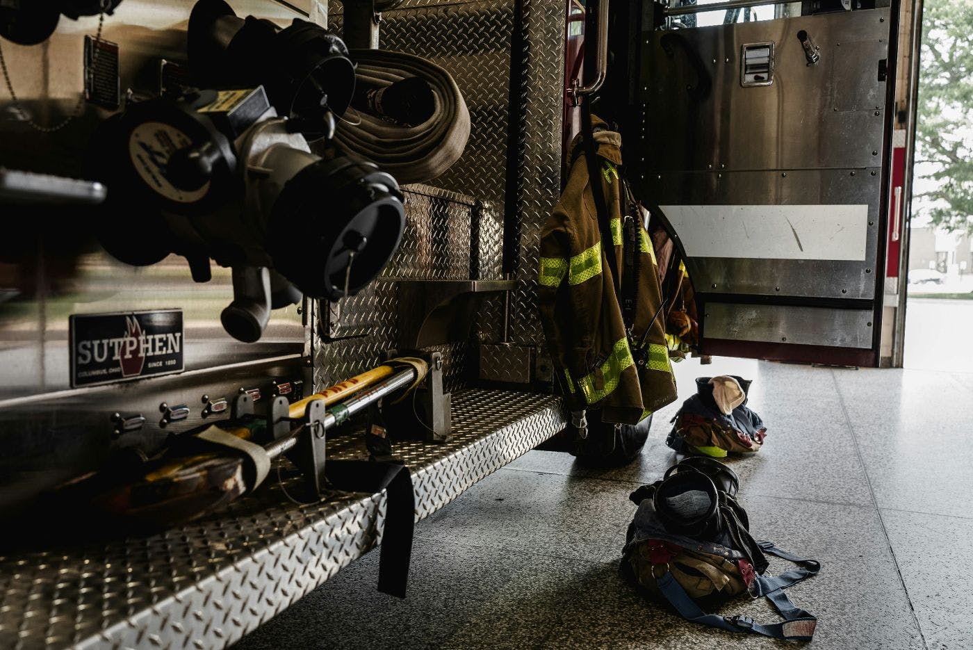 Fire fighter's gear on the floor next to a fire truck