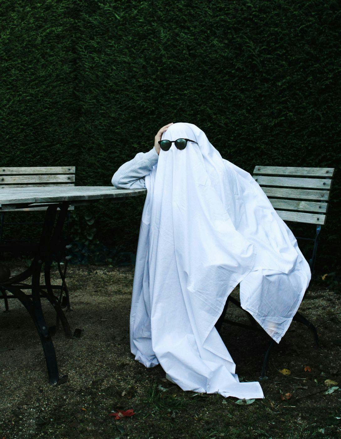 A "Ghost" wearing sunglasses sitting at a park table
