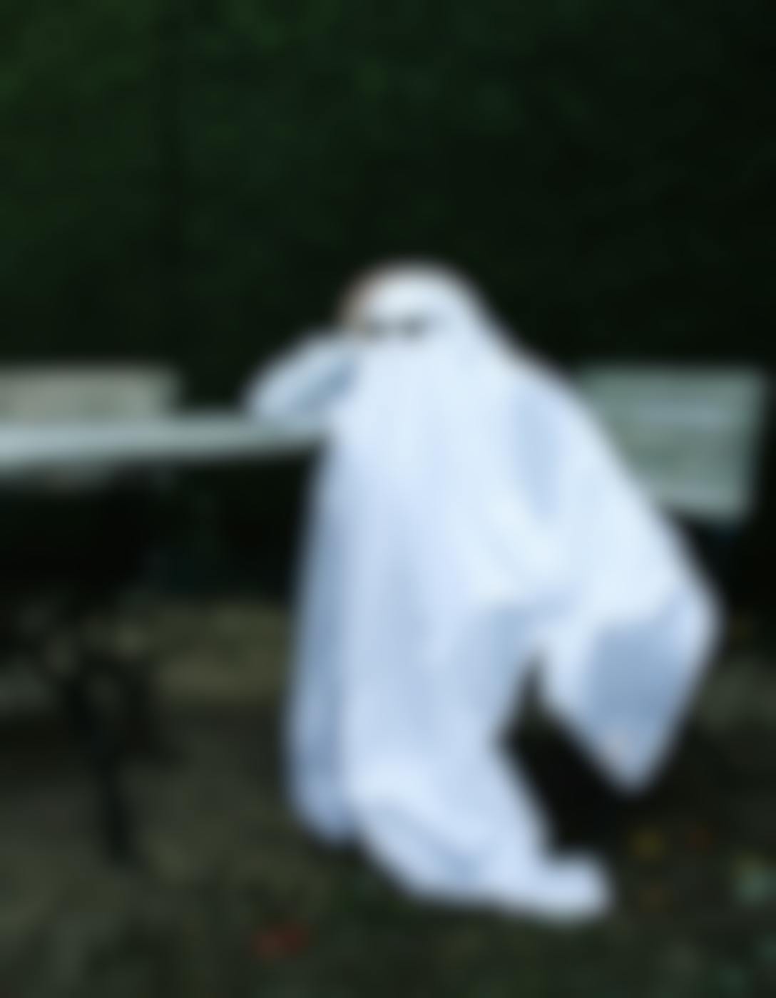 A "Ghost" wearing sunglasses sitting at a park table
