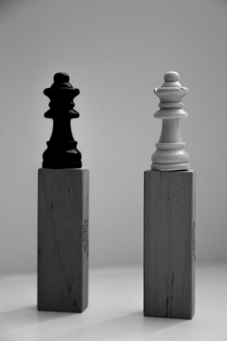  2 chess pawns one black, one white on little plinths