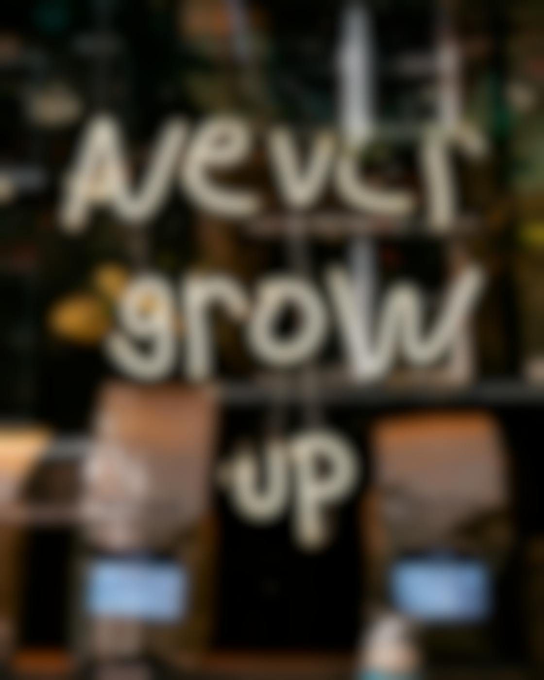 A white neon sign in a coffee shop reading Never Grow Up