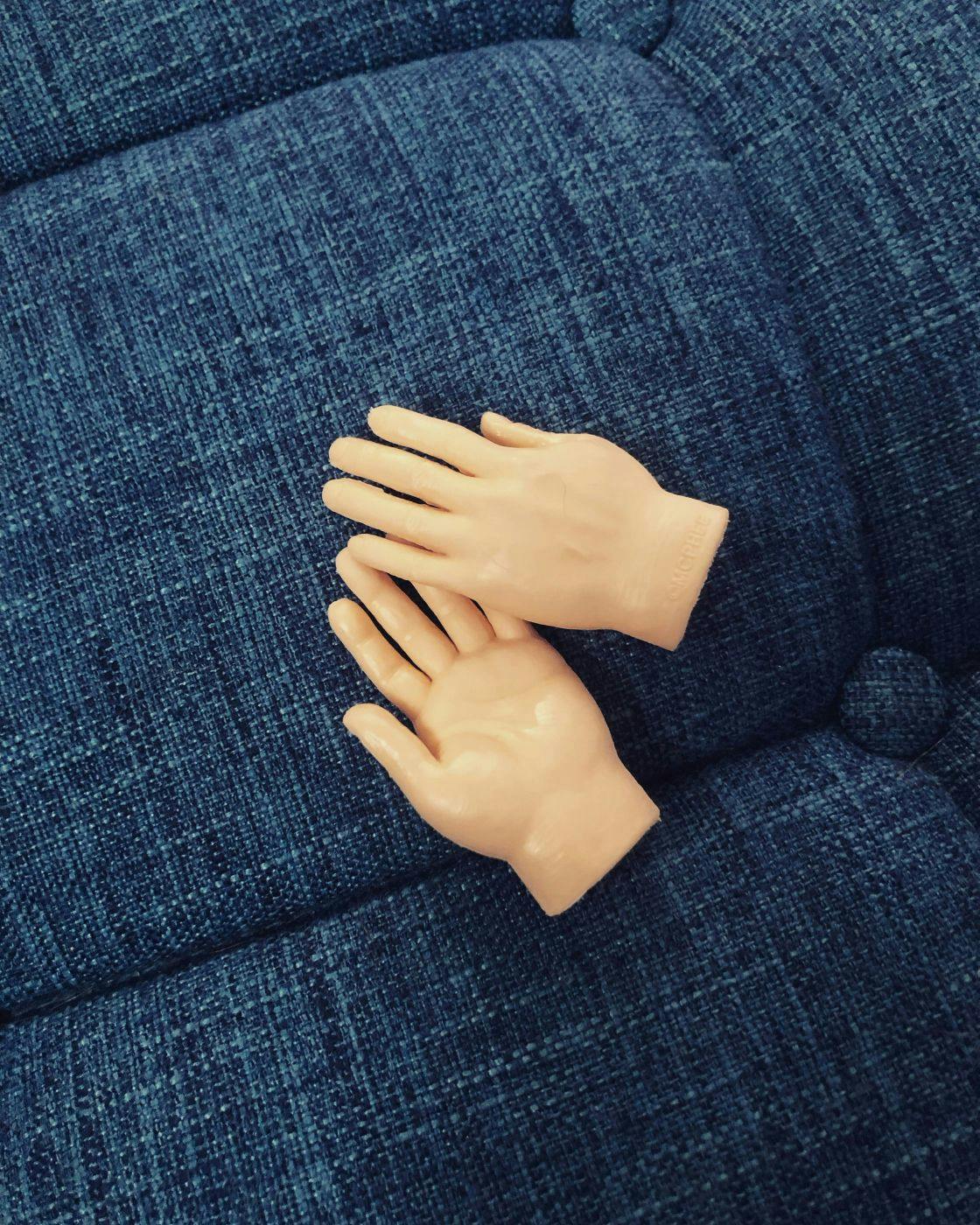 A pair of fake hands on a blue couch