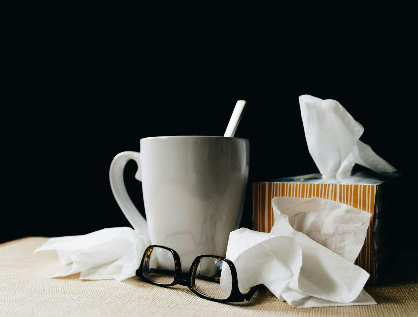 A coffee cup, pair of glasses and a box of facial tissues