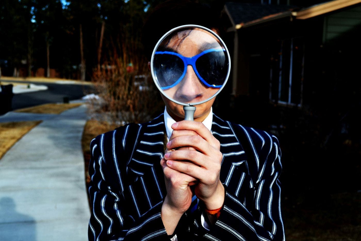 A person looking through a magnifying glass so his nose and glasses are enlarged