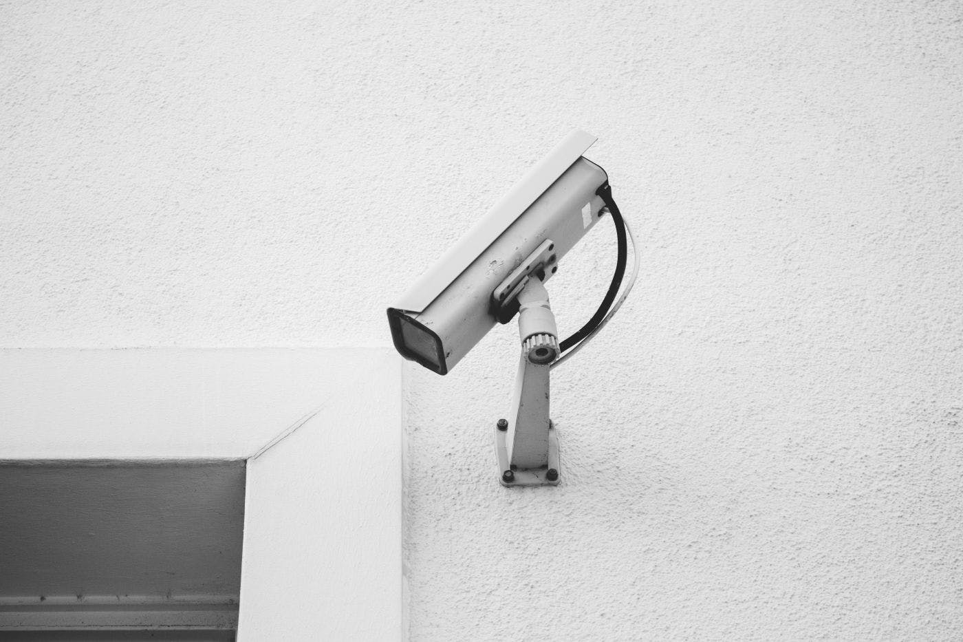 A white Surveillance camera on a white wall. 