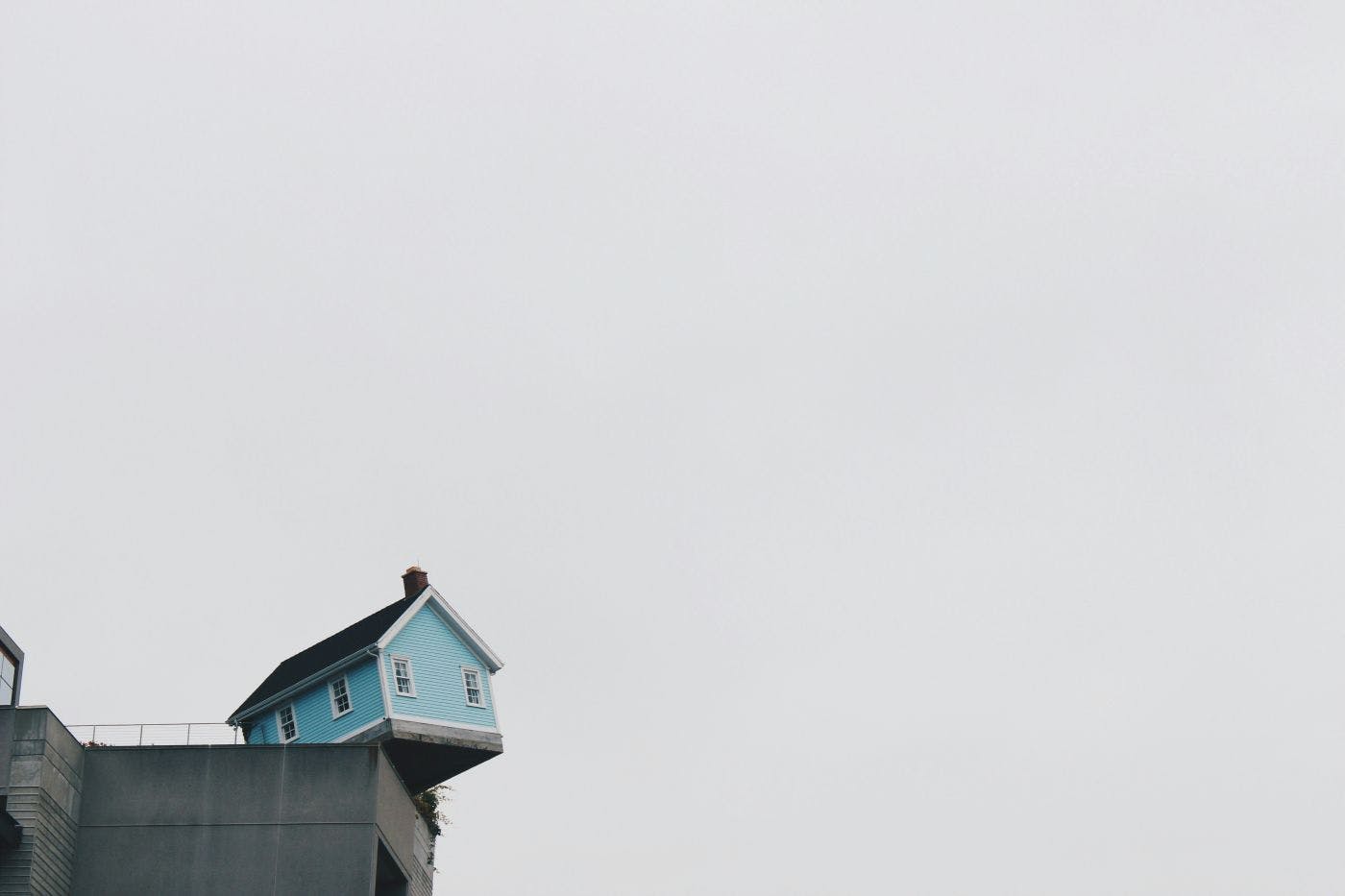 A blue house hanging over the edge of a parking lot