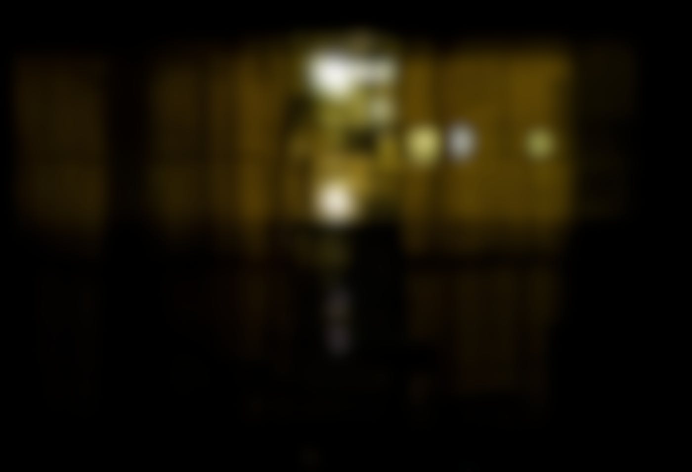 A dimly lit room with blinds on the windows and a bike in the room