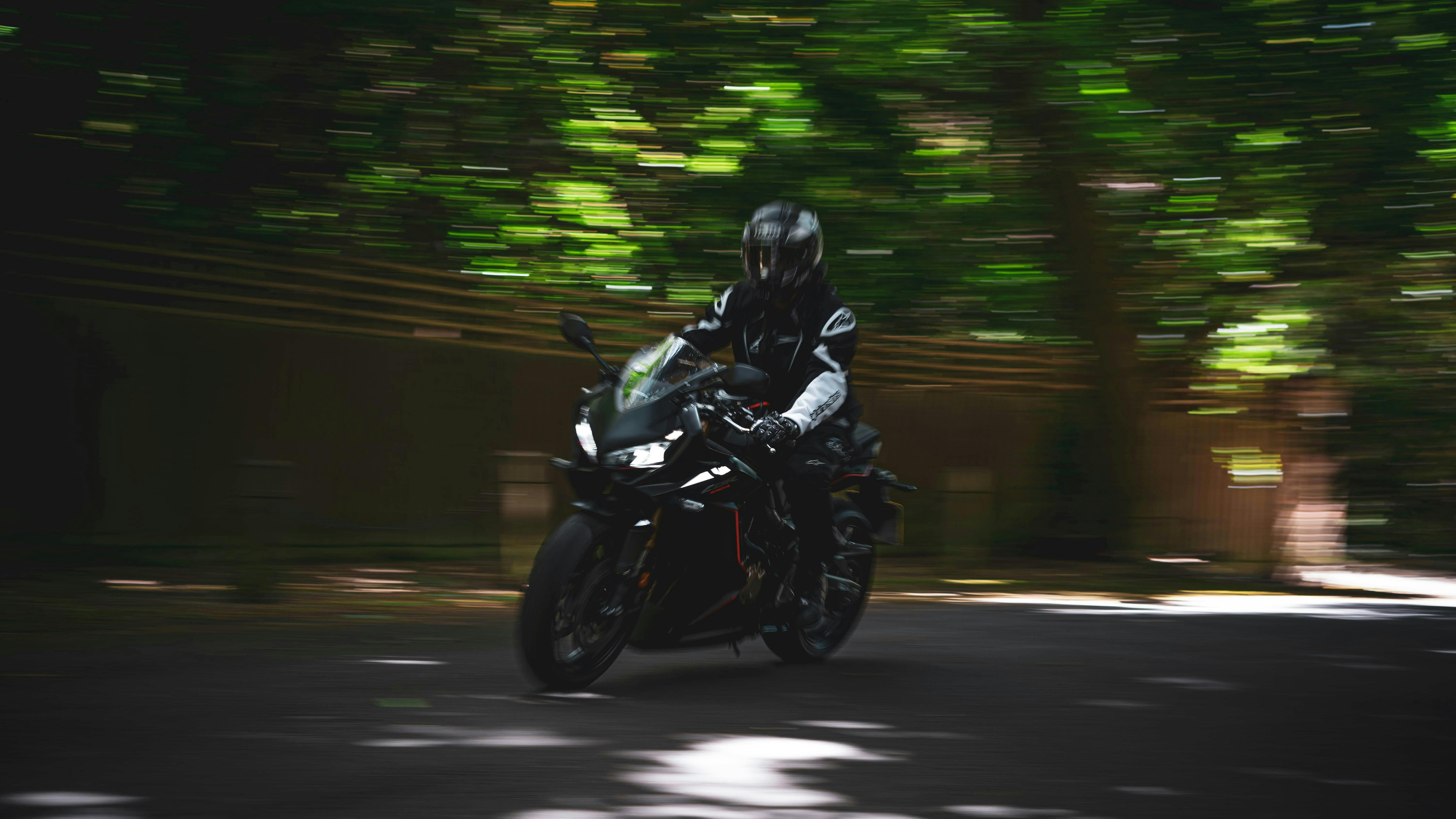 A person on a black motorcycle speeding  by the camera
