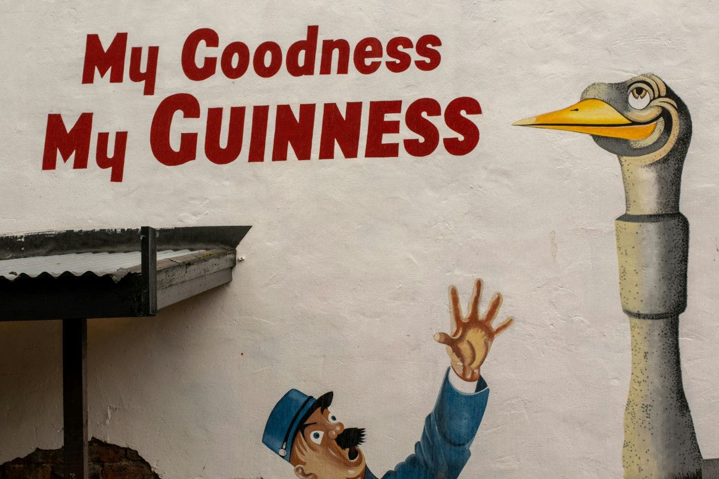 A Guinness wall ad My Goodness, My Guinness, with a bobby reaching for an Ostrich that has a pint glass in its throat