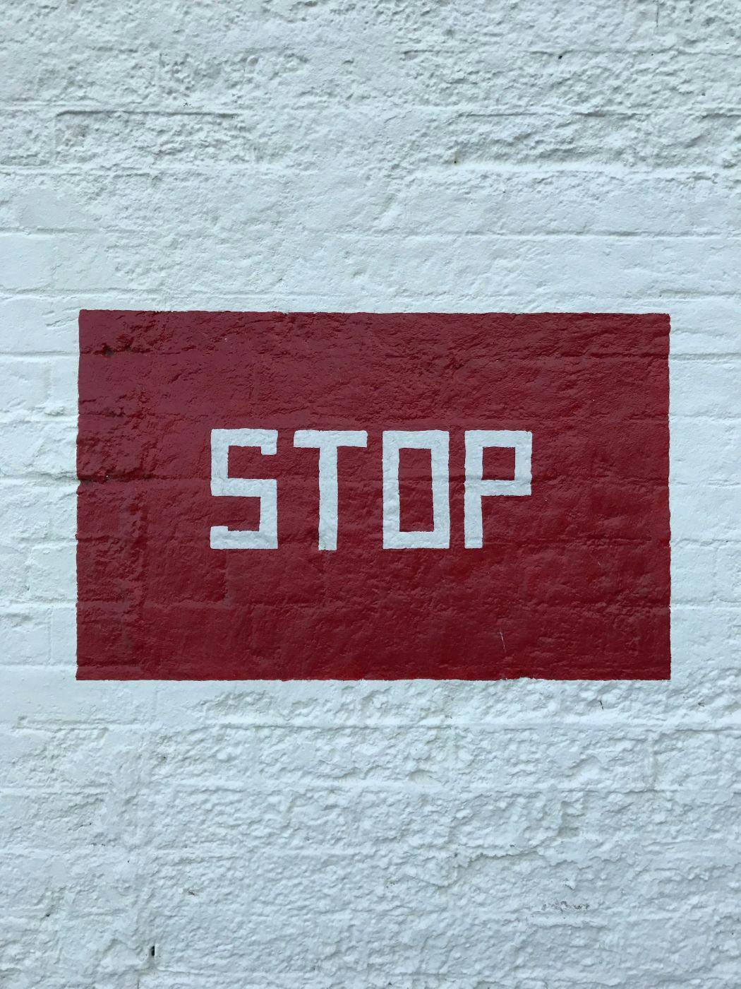 A red rectangle with white letters in it spelling stop on a white wall