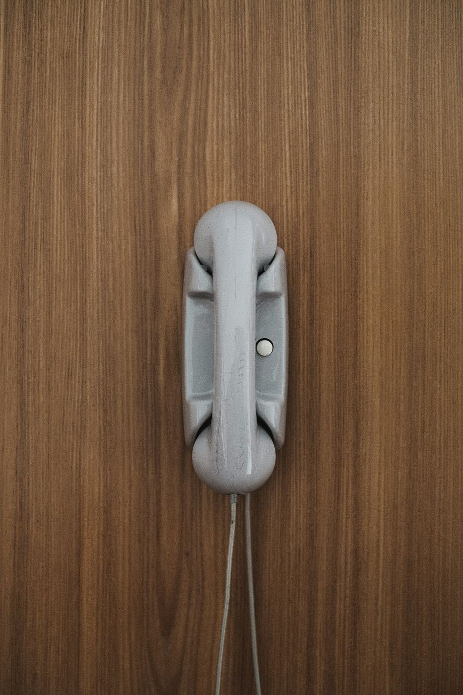 A landline phone on a faux wood wall