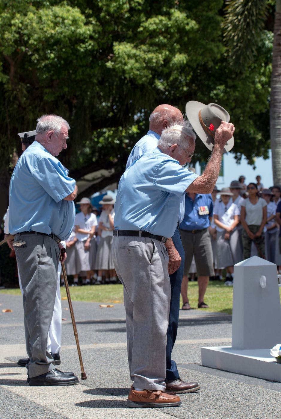 Three older gents paying their respects at a grave