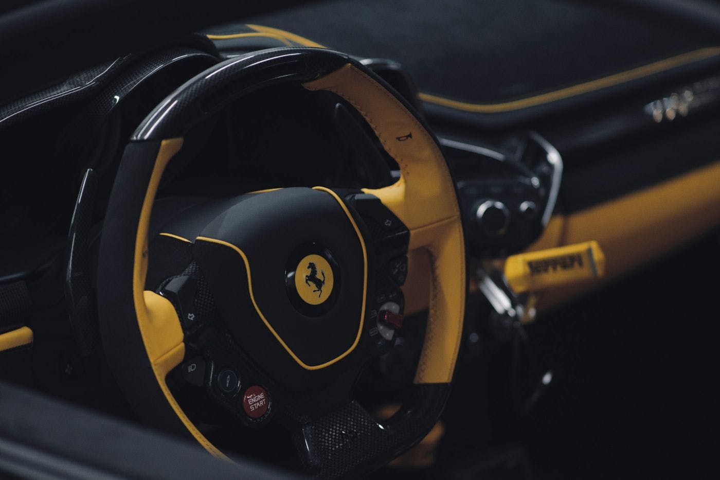 The black and yellow dash and steering wheel of a Ferrari