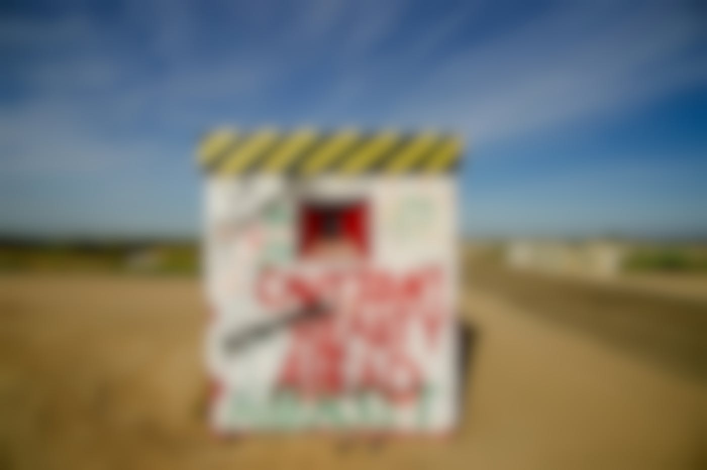 A graffitied guard shack with Caution Reality Ahead in red