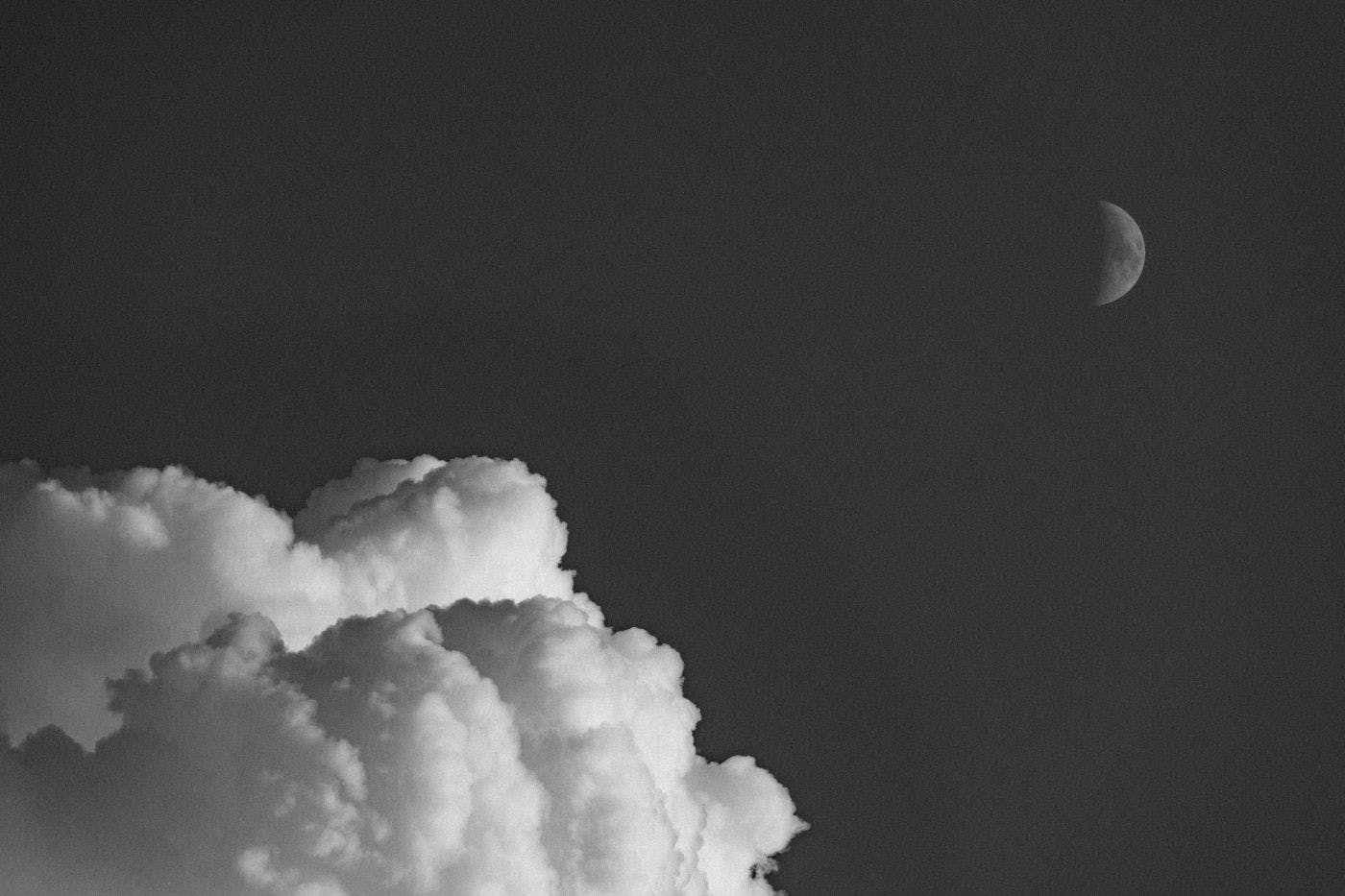 Black & white of puffy clouds and a visible half moon