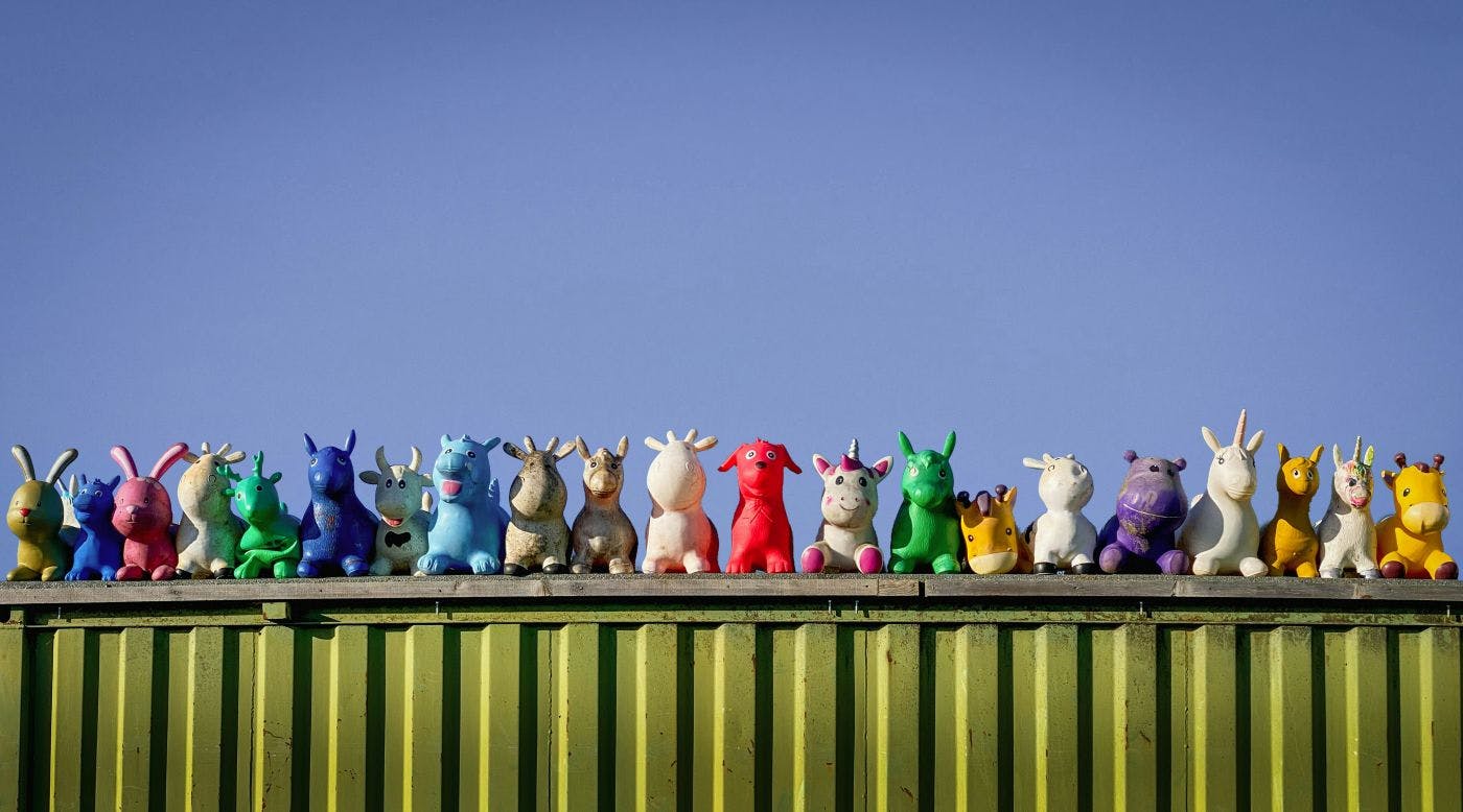 A line of stuffed animals atop a green shipping container