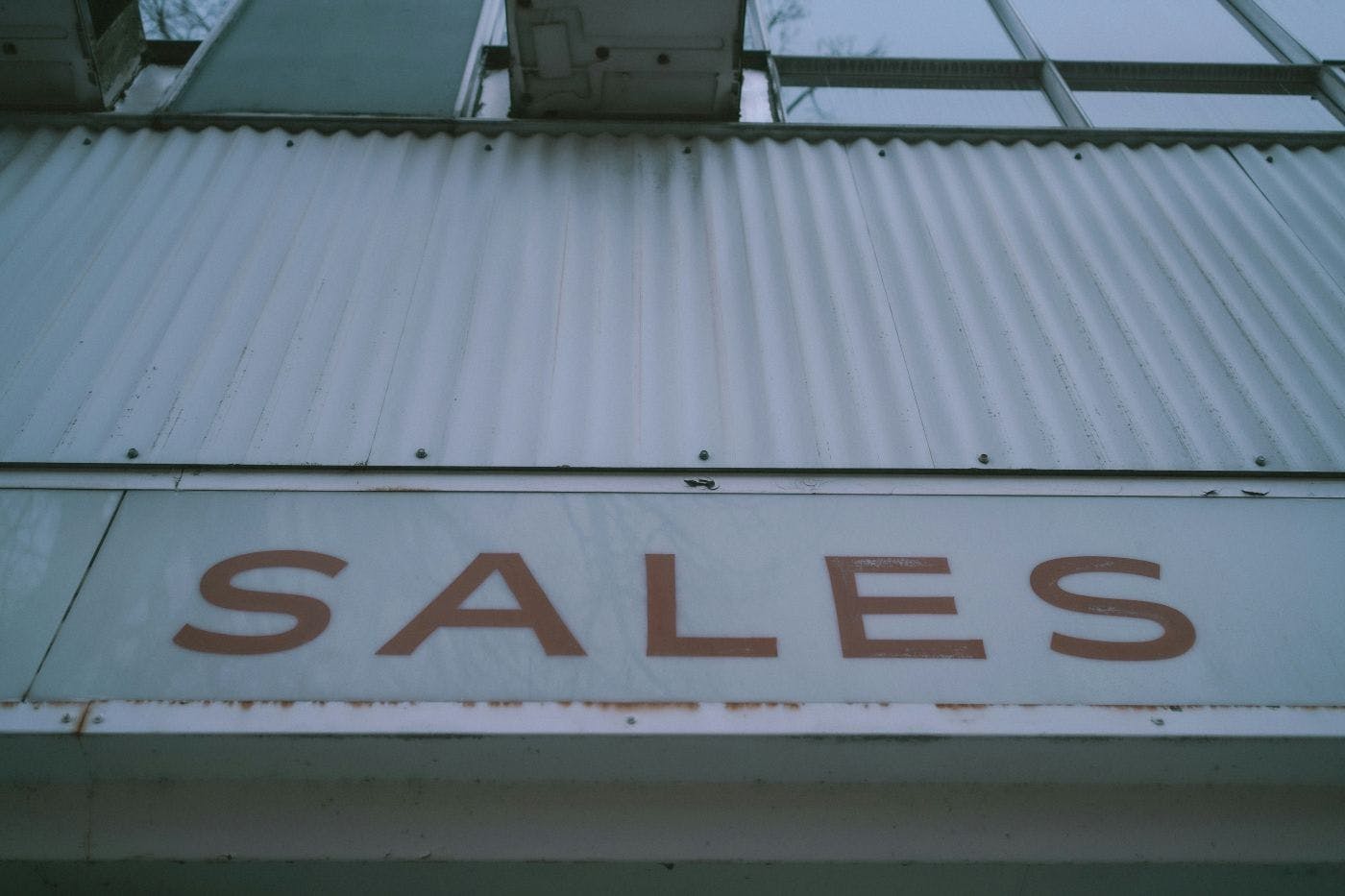 A tin sign on a building reading SALES