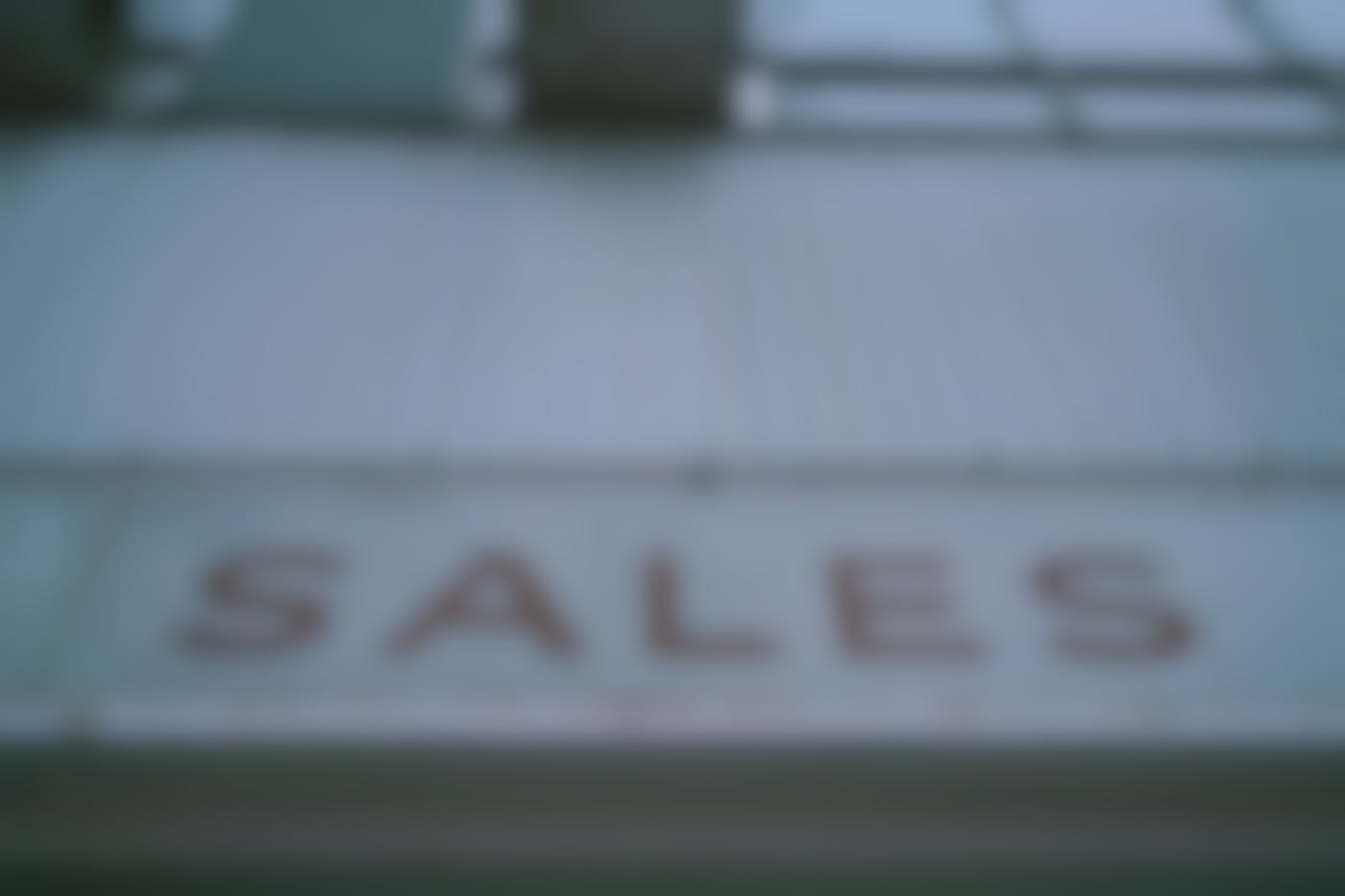 A tin sign on a building reading SALES