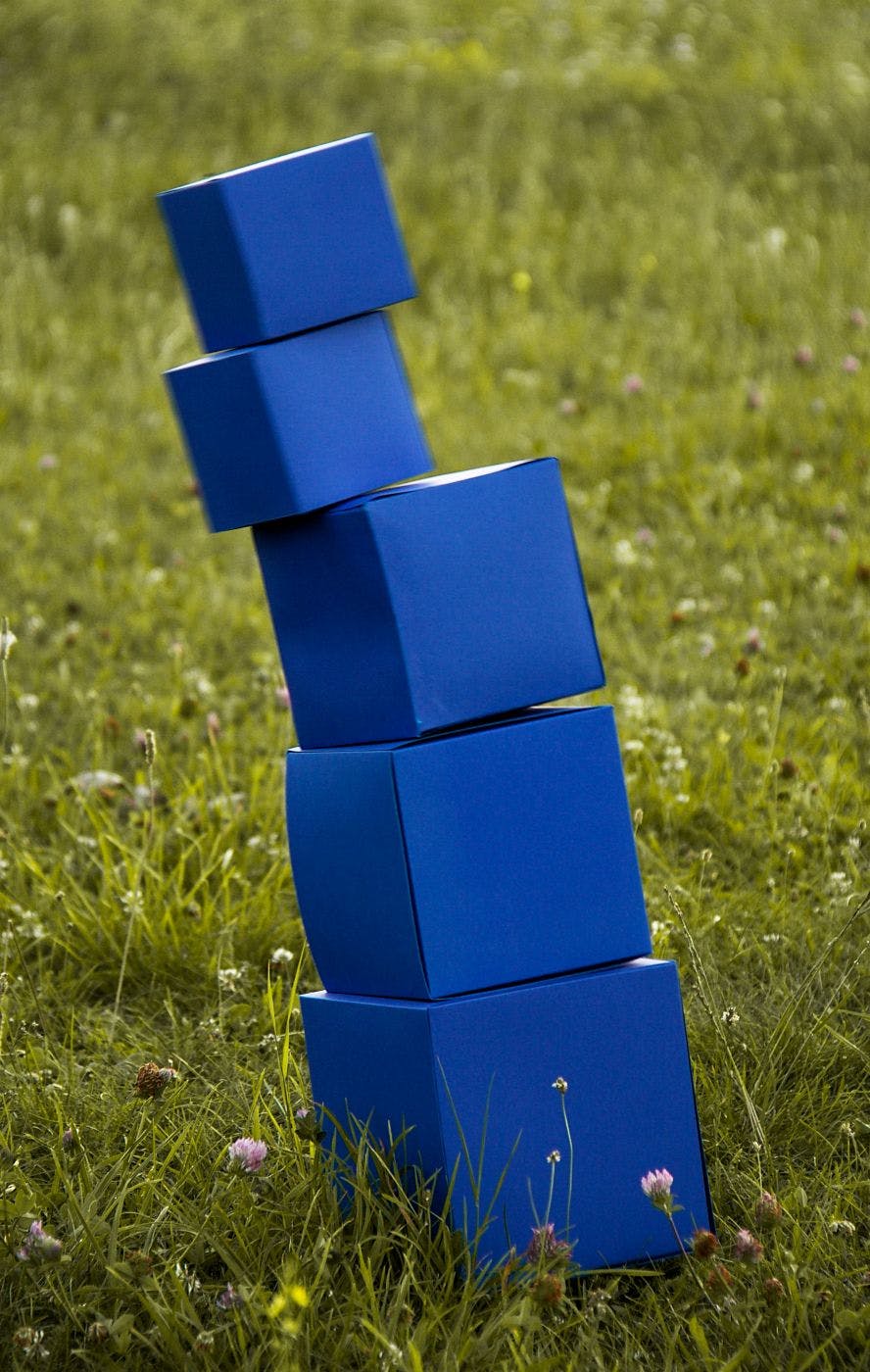 A stack of blue boxes, mid tumble, in a field