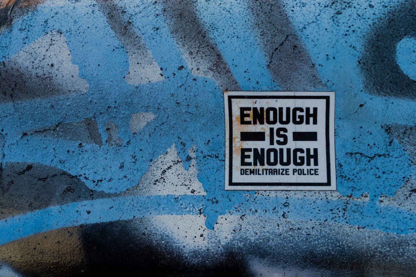 A poster on a graffitied wall reading Enough is Enough