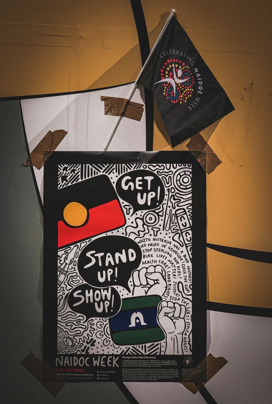 A colorful sign reading Get Up! Stand Up! Show Up!