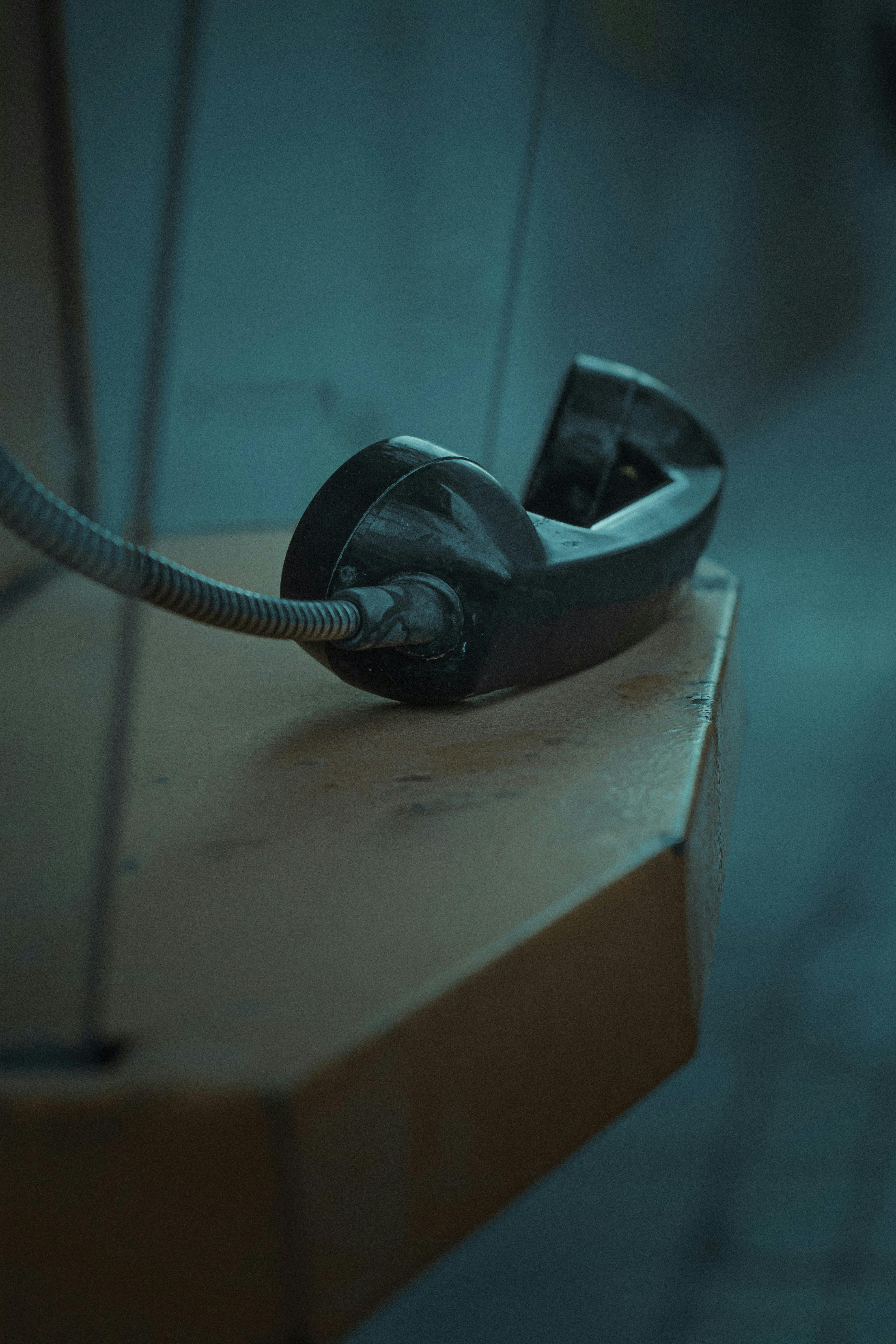 The black handset of a landline sitting on a shelf