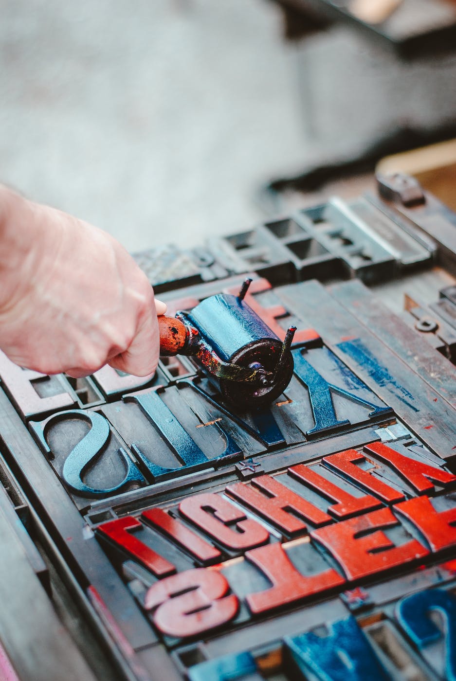 A person using a brayer to ink type to be printed