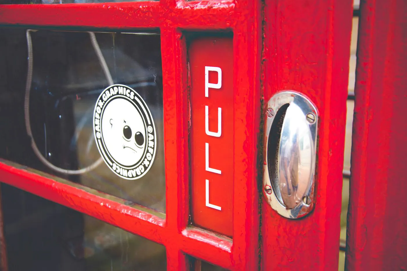 The door of a red British phone box with the word PULL in white