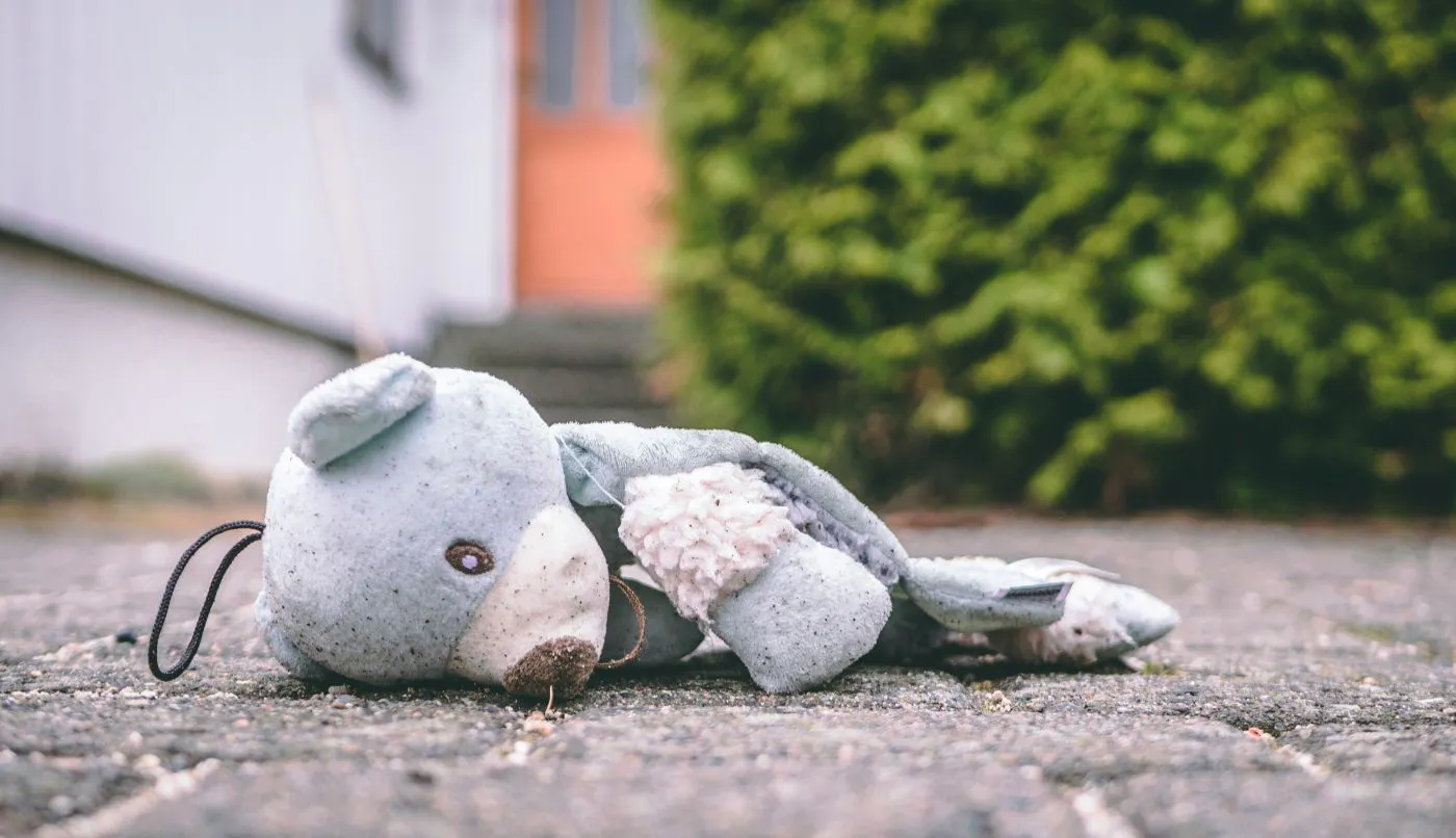 A pale blue teddy bear mauled and left on the pavement