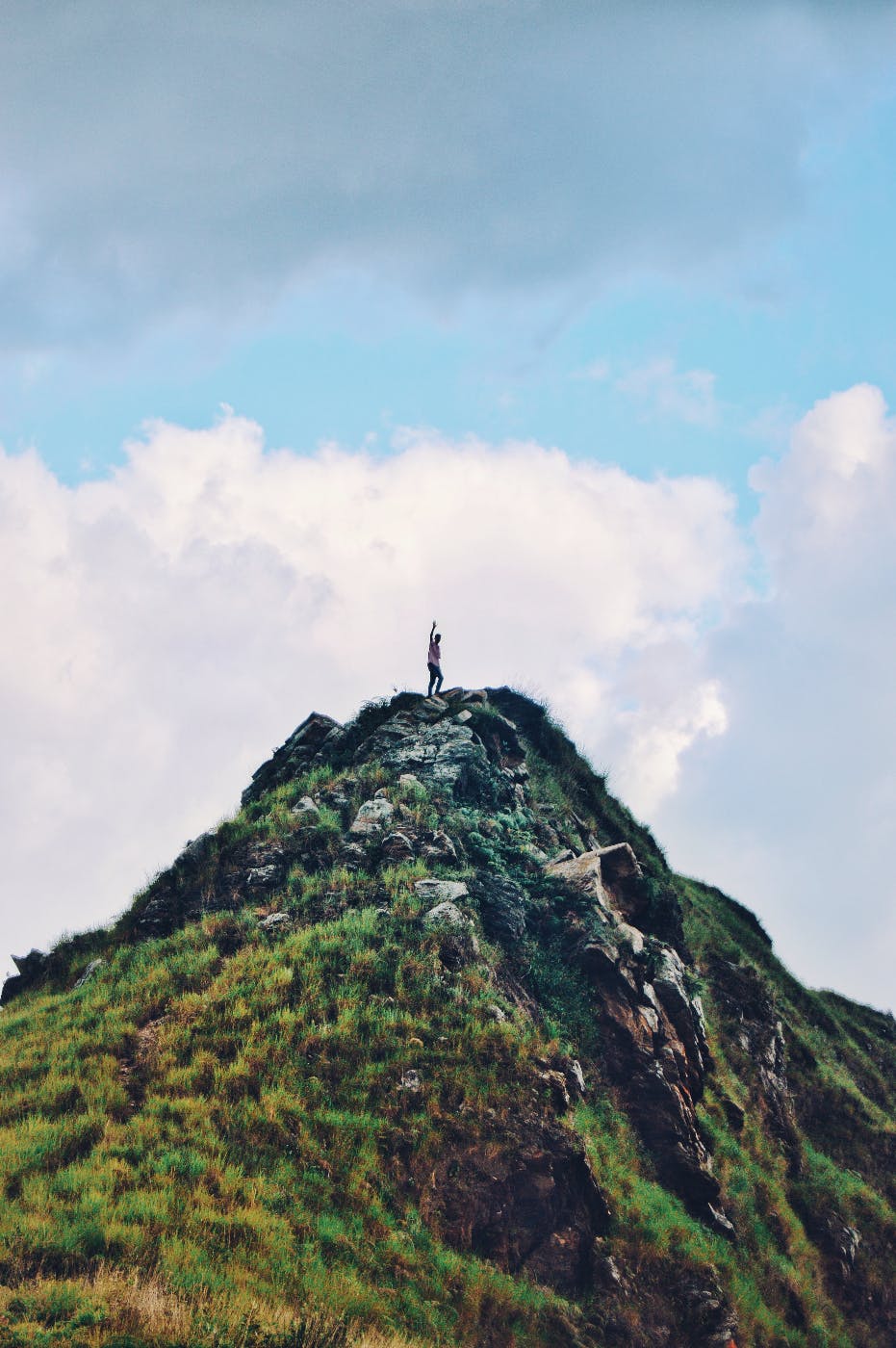 a man waving at the top of a mountain
