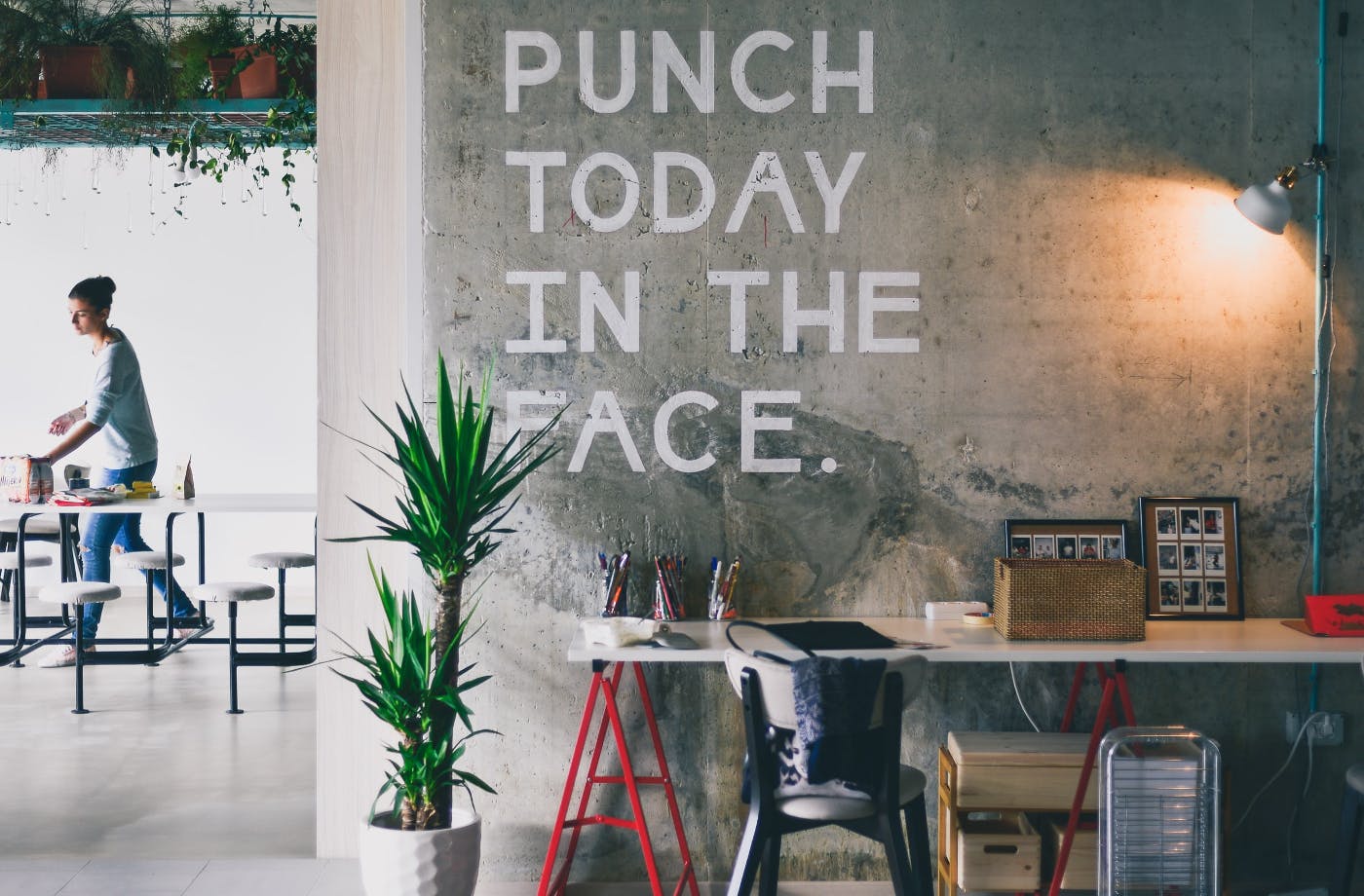 A wall over an office desk with Punch Today In The Face written on it.