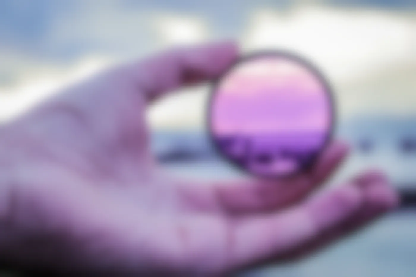 A person holding a camera lens filter