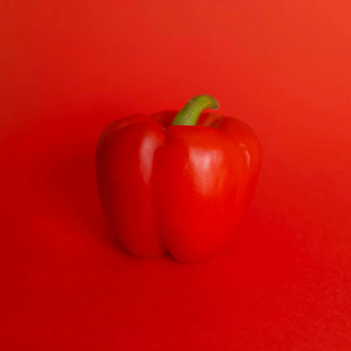 A red bell pepper against a red background