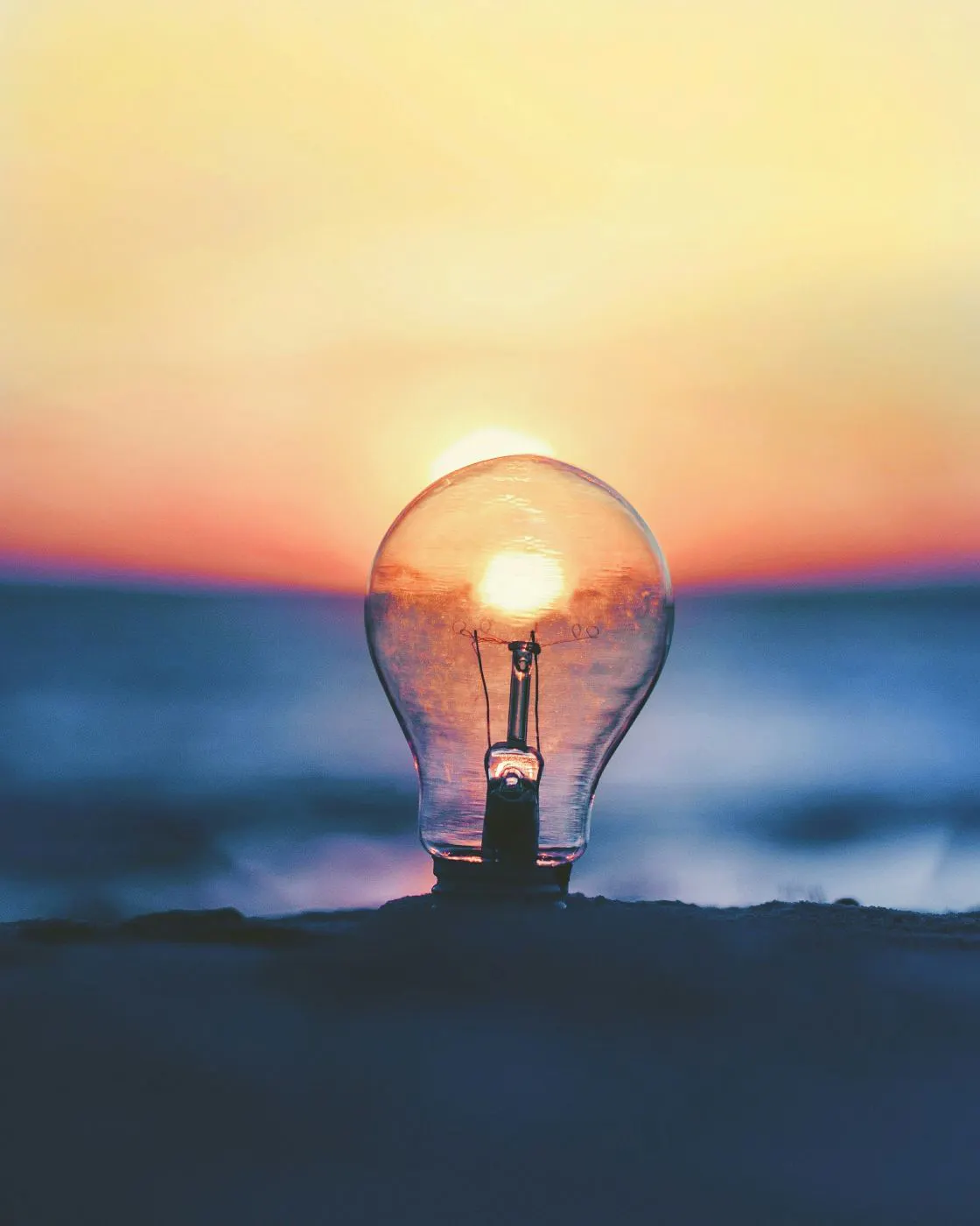 A lightbulb buried in sad with the sunset caught in it