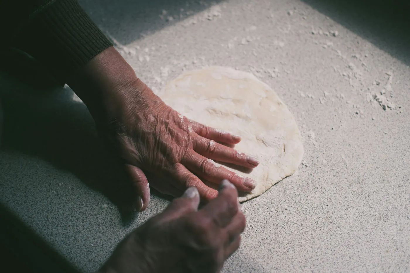 A woman's hands flattening out dough