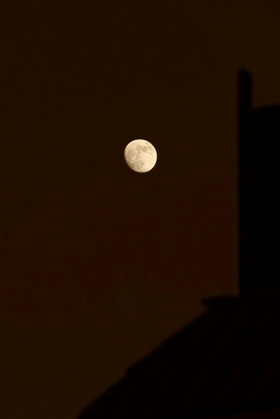 The moon high above a silhouetted building