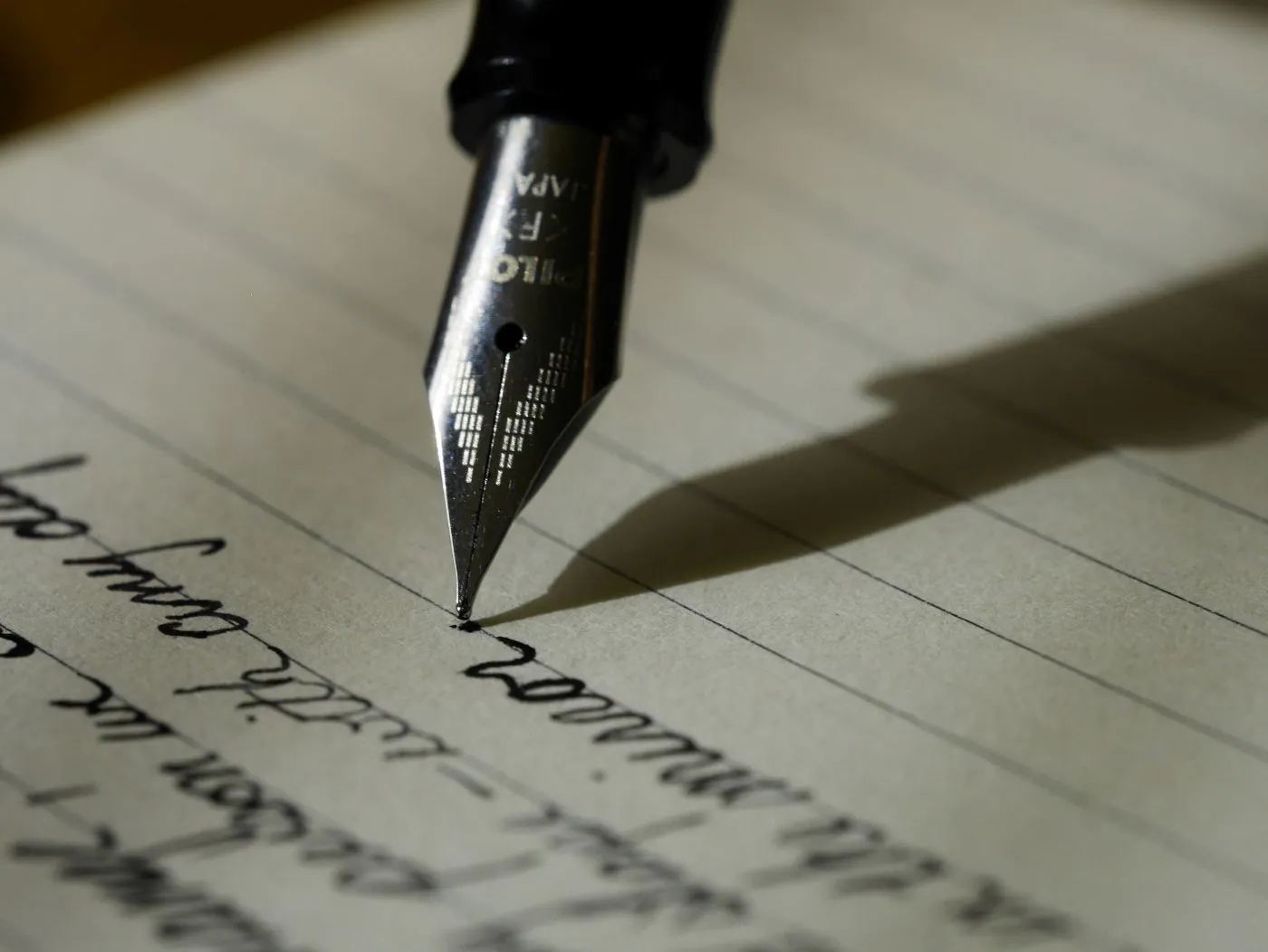 A close up of a pen nib writing on lined paper
