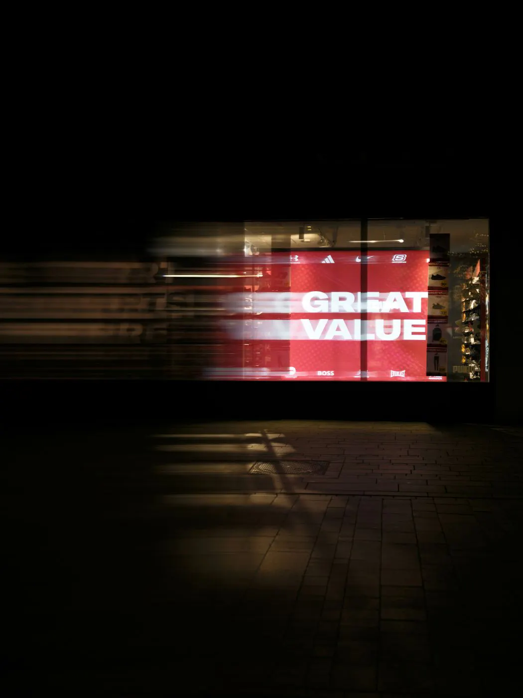 A sign in a storefront on a dark street reading GREAT VALUE