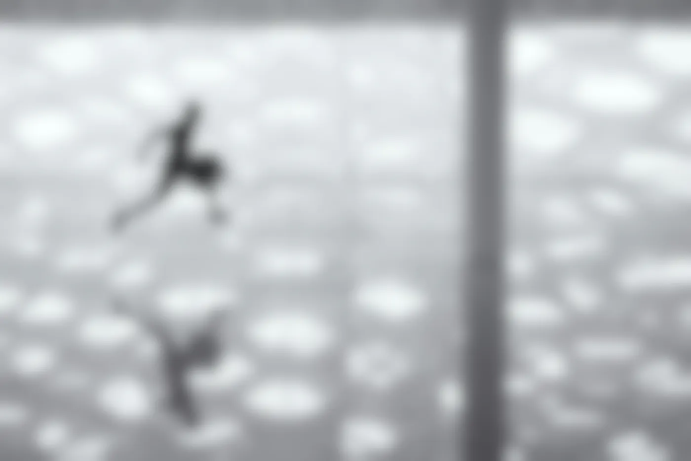 A man with a suittcase running across a reflective floor in an airport