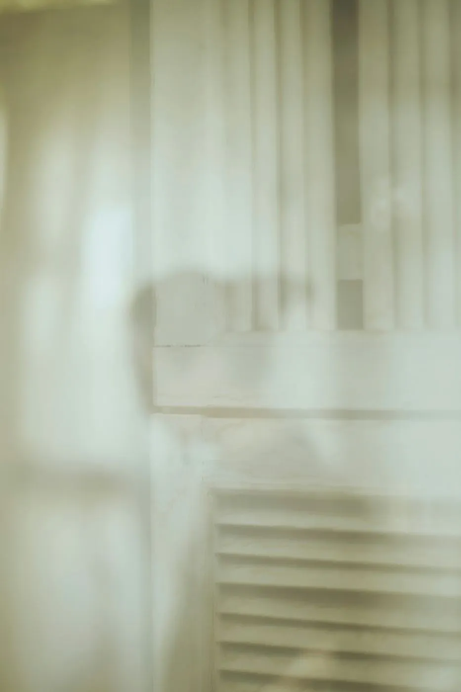A white wall and the faint shadow on a woman