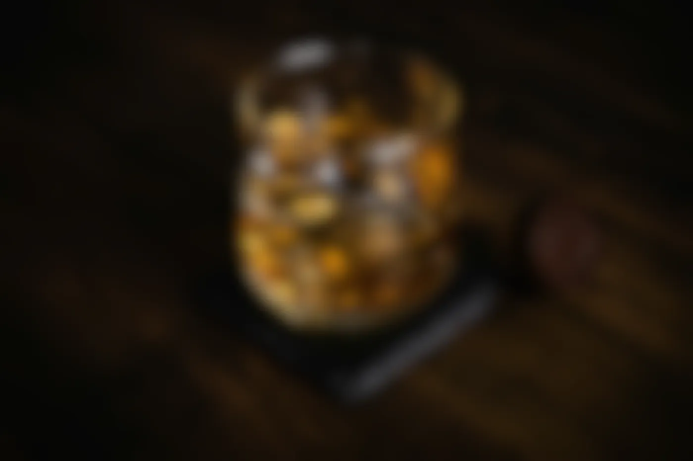 A glass of bourbon on a dark wood table