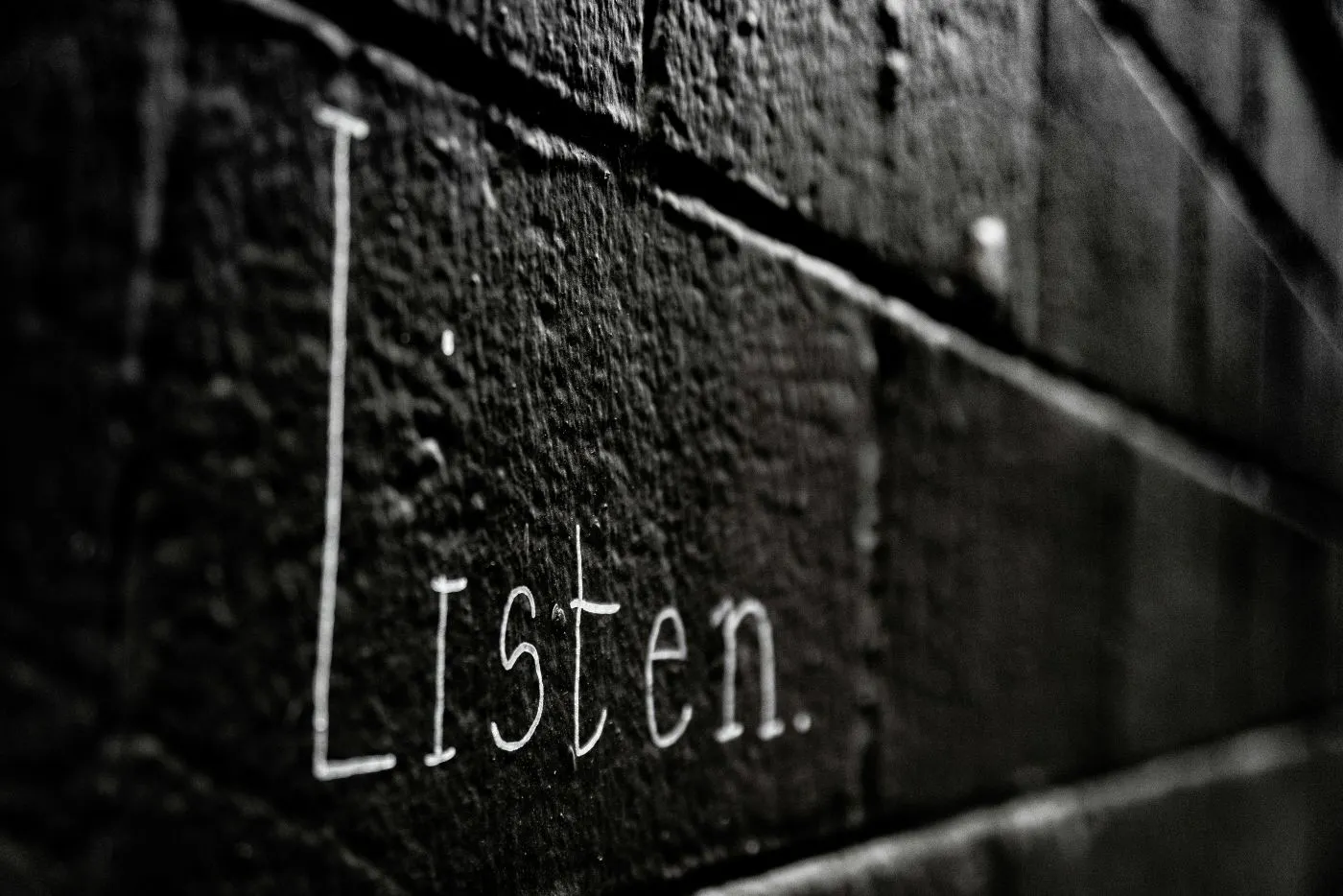 A black wall with the word listen written on it in white