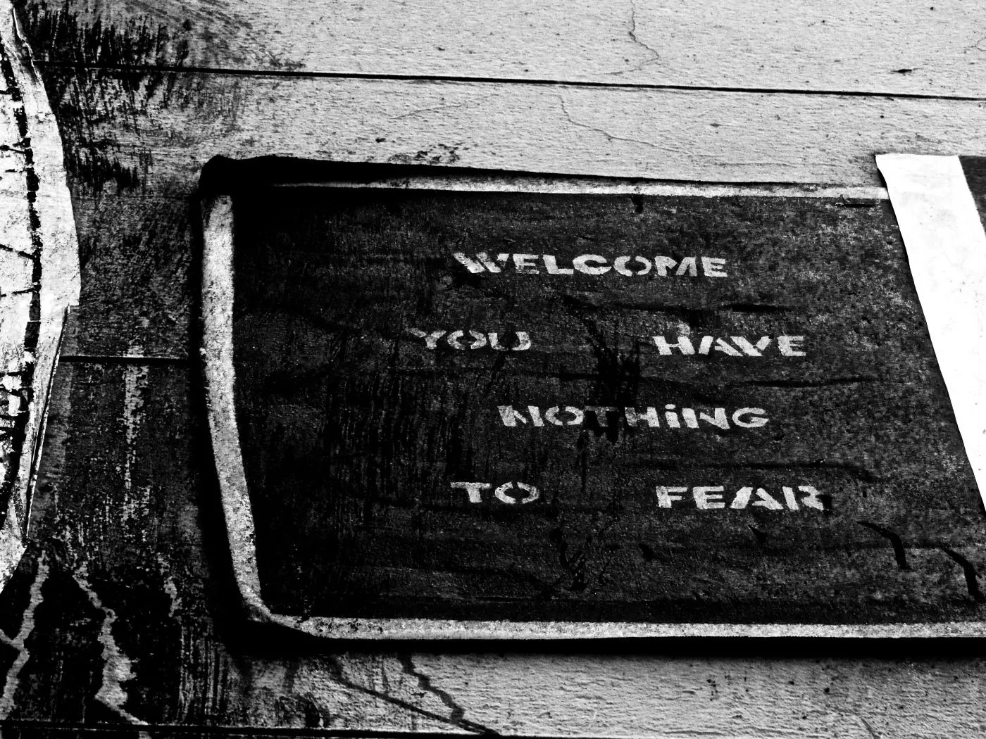 Black and white mage of a door mat with Welcome You Have Nothing To Fear on it