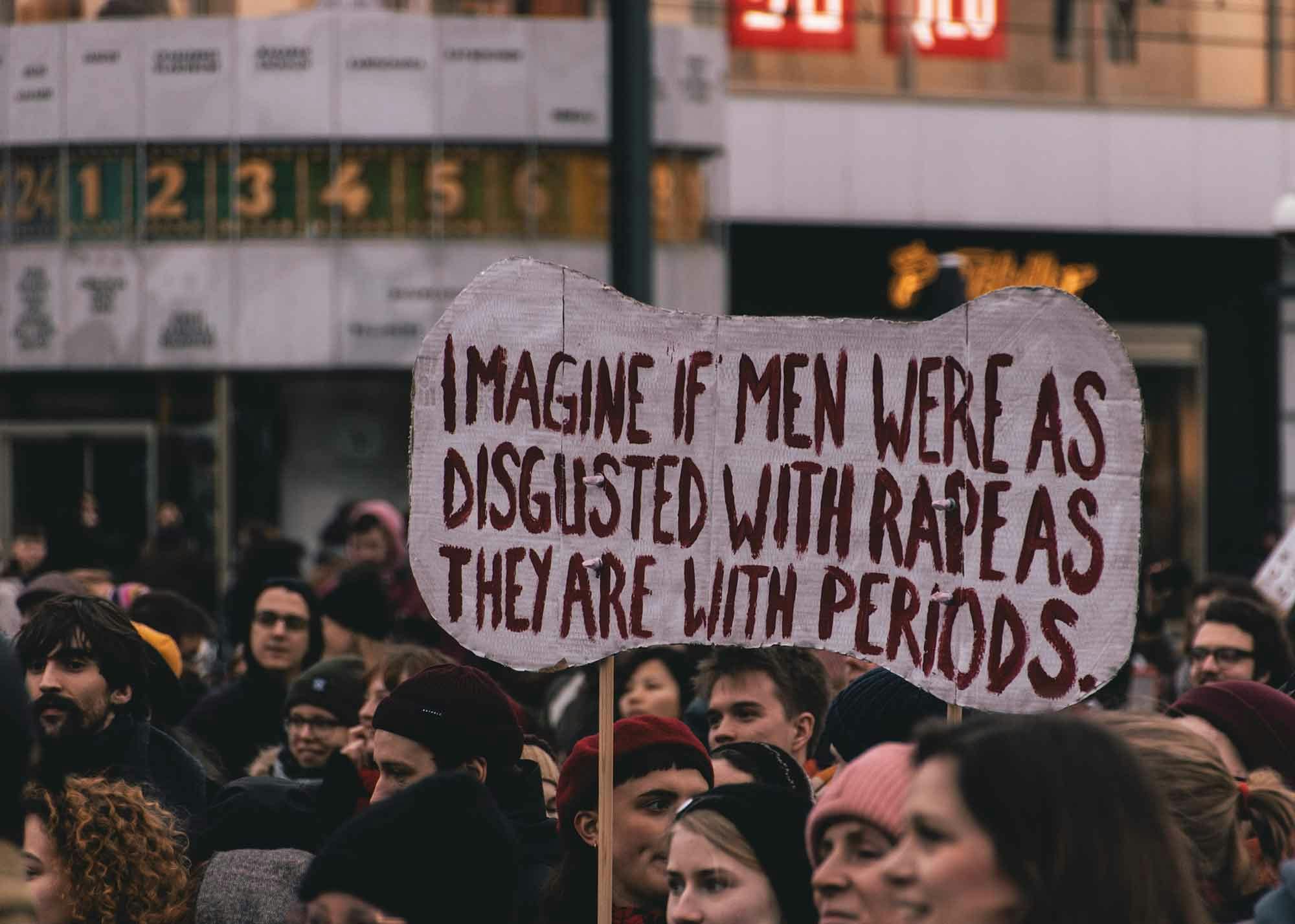 A woman holding a sign at a protest about rape