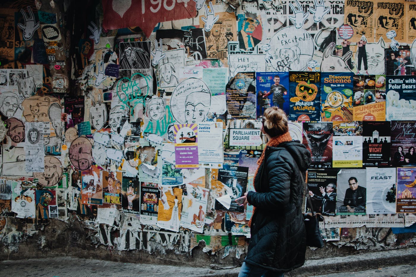 A woman in front of a wall that is completely covered with handbills