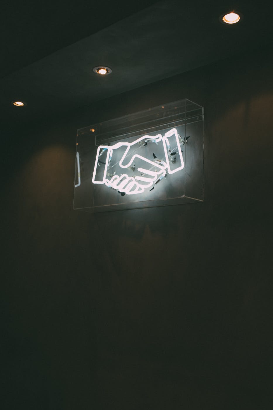 A white neon sign of a hand shake