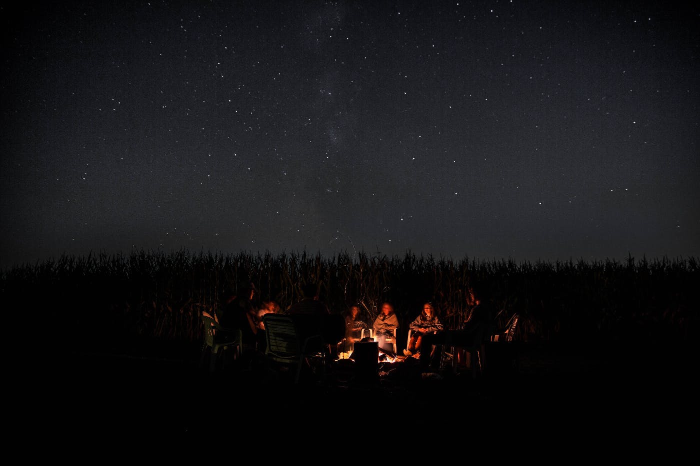 People sitting around a camp fire under a starry sky