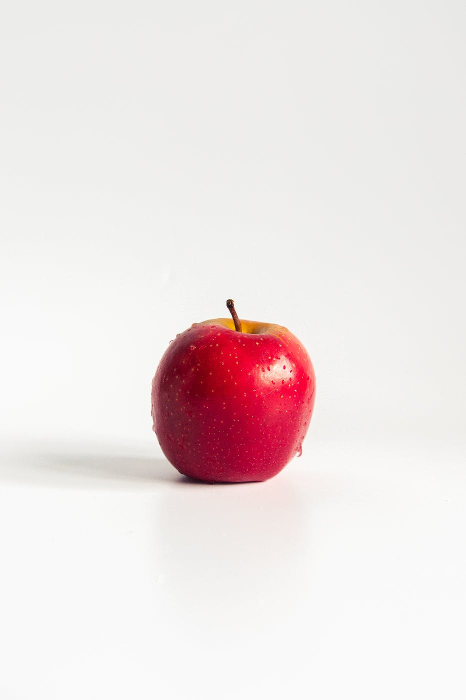 A dew covered apple against a white background