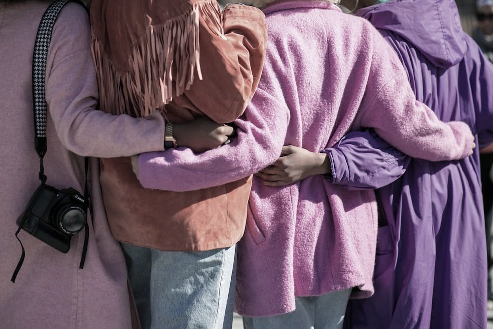 four women with arms around each other