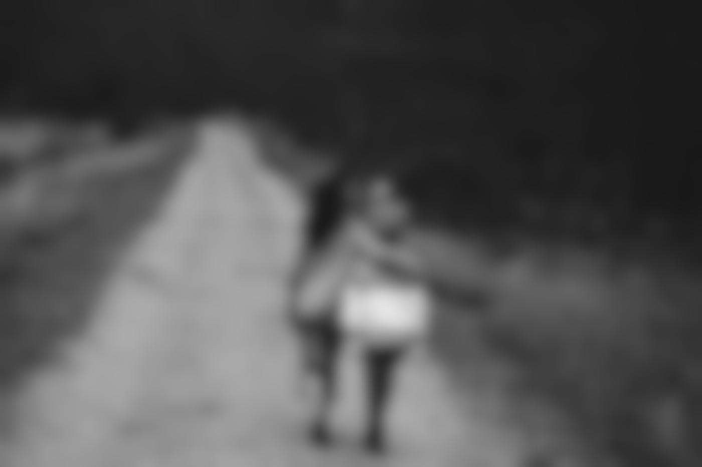 Two small children walking down a country road, one has her arm around the shorter one's shoulders